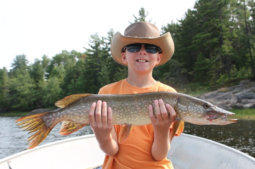 Northeastern Ontario Northern Pike Fishing with a Boy in orange shirt holding a nice sized Fish