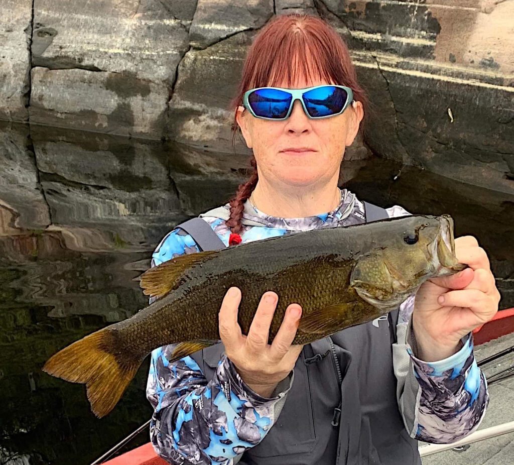 French River Smallmouth Bass being held by a red headed, Great Canadian Female Angler.