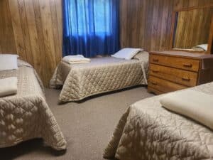 Bear Cub cottage room 3 with 3 single beds and a wooden dresser.